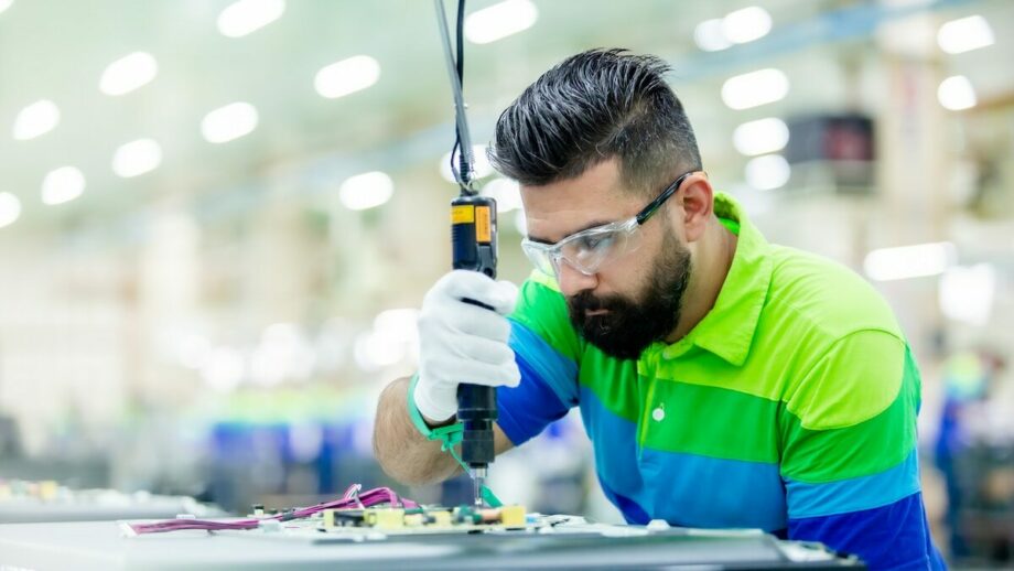 A man working on an electronic device in a factory.