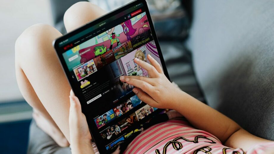 A girl is sitting on a couch with a tablet computer.