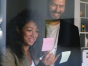 A man and a woman standing in front of a glass door.