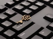 An ornate key lies atop a black computer keyboard, positioned across the Shift and Enter keys.